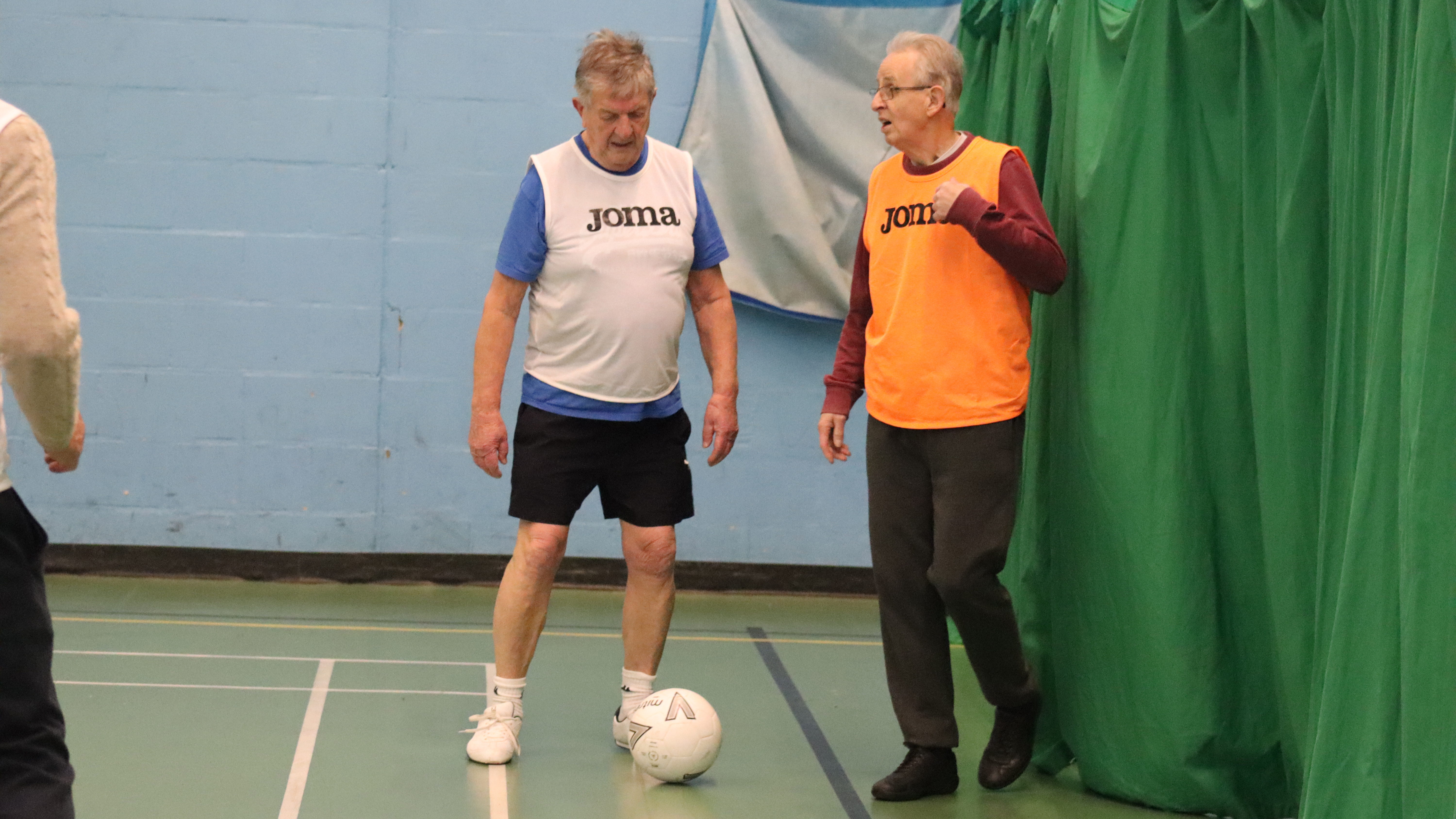 Two players standing over the ball in walking football 