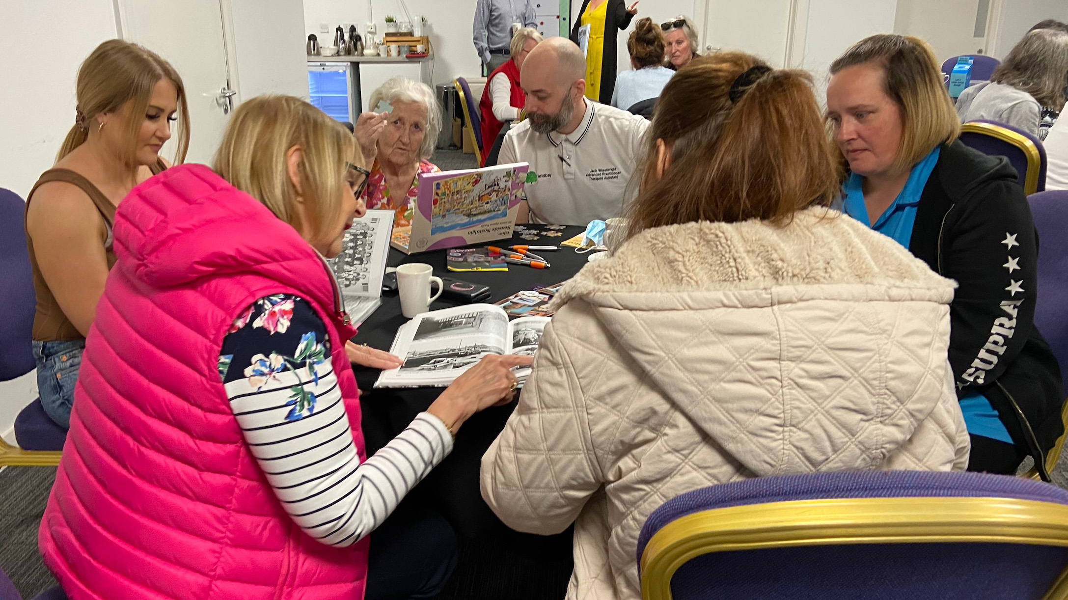 People sit around a table completing puzzles at the dementia friendly coffee morning