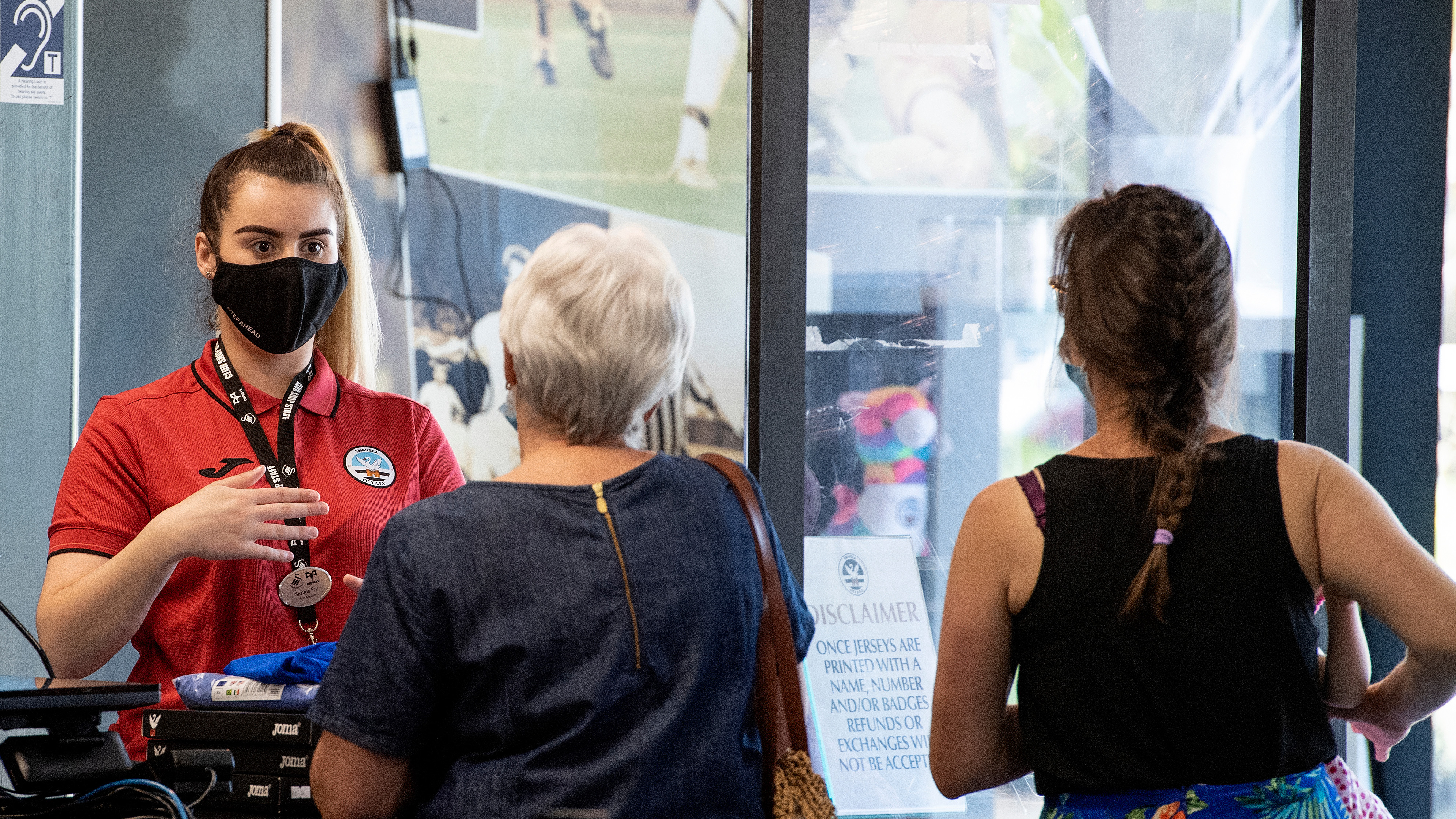 Two supporters are served by a staff member at the Swansea City club shop