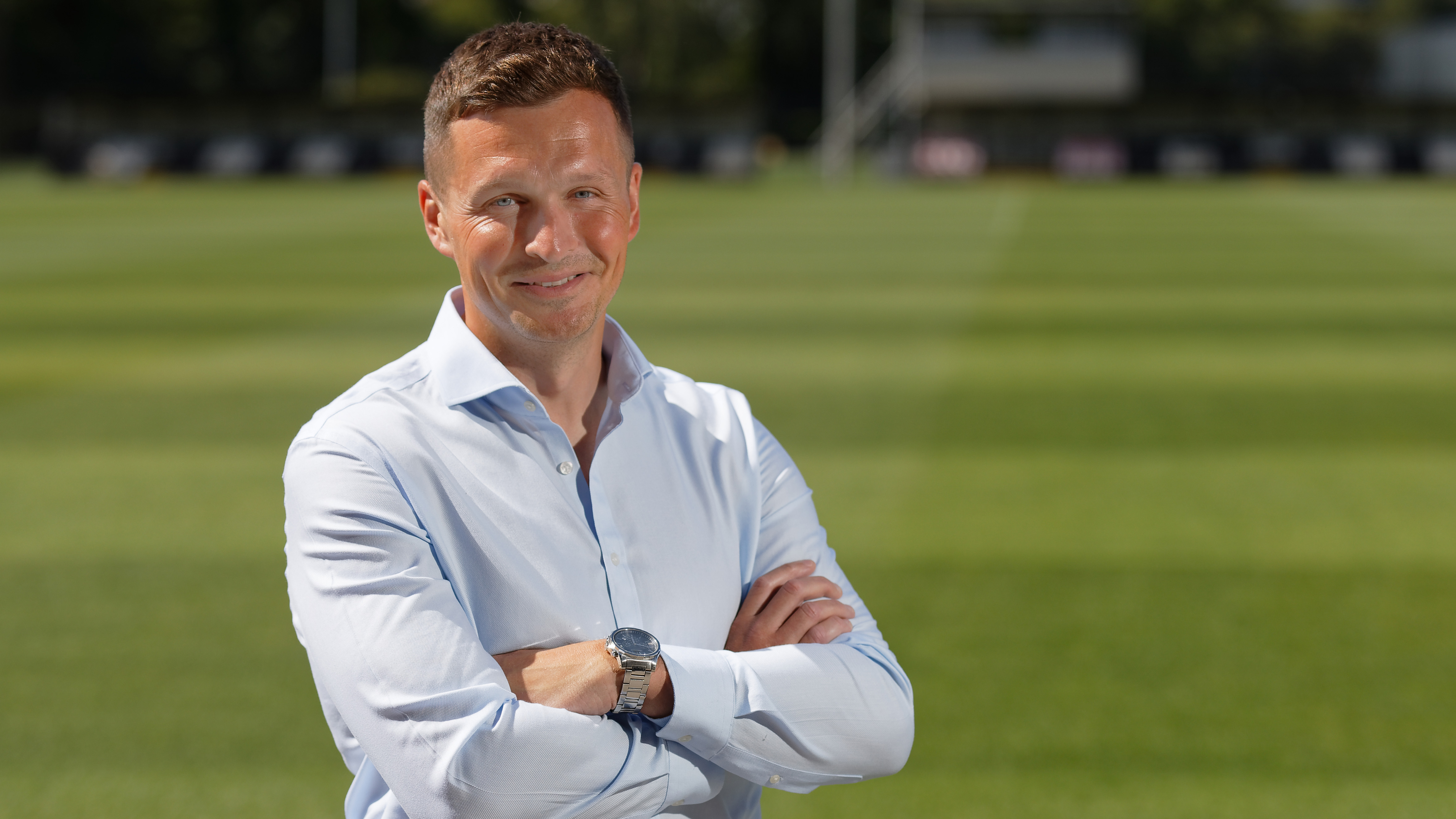 Profile photo of Andy Goldie with his arms folded in front of Academy training pitches