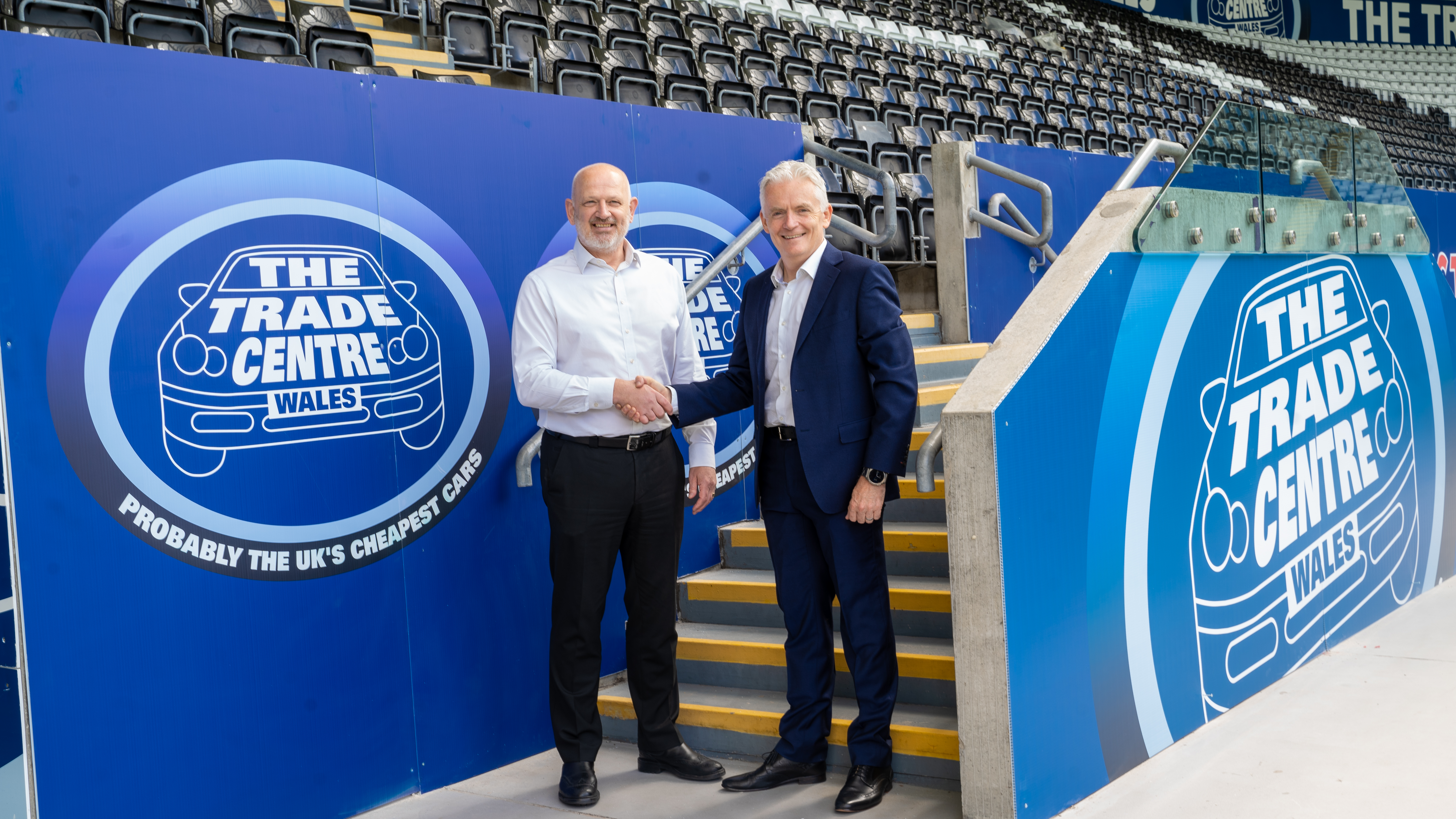 Swansea City chief executive Julian Winter and Trade Centre Group CEO Tim Carr shake hands in front of new Trade Centre branding in the East Stand 