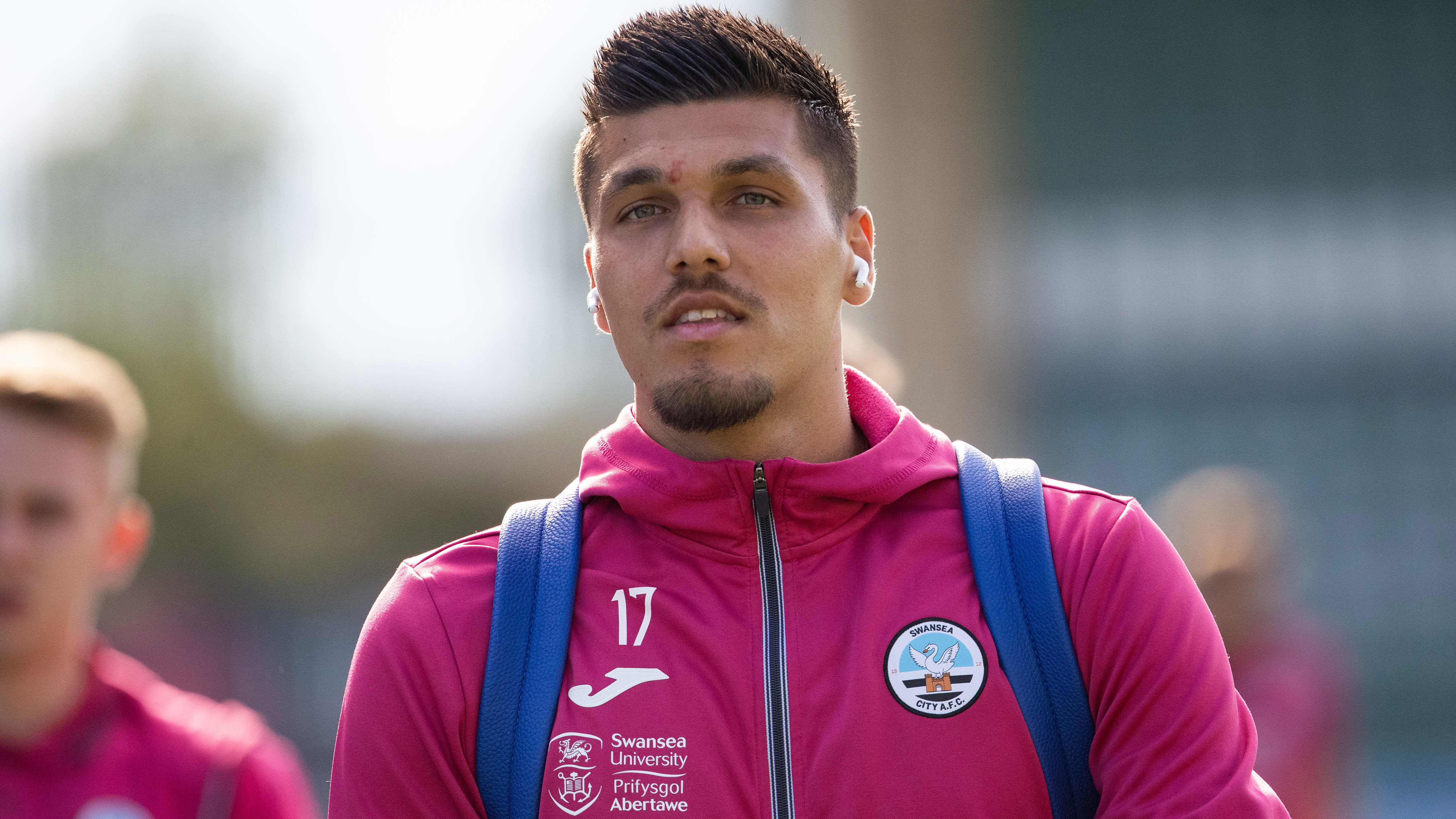 A close of Joel Piroe in a pink Swansea City jacket arriving at Plymouth Argyle's ground