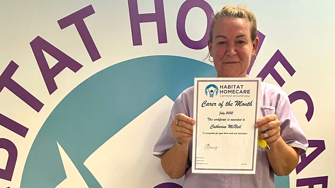 Cath holds up her carer of the month certificate