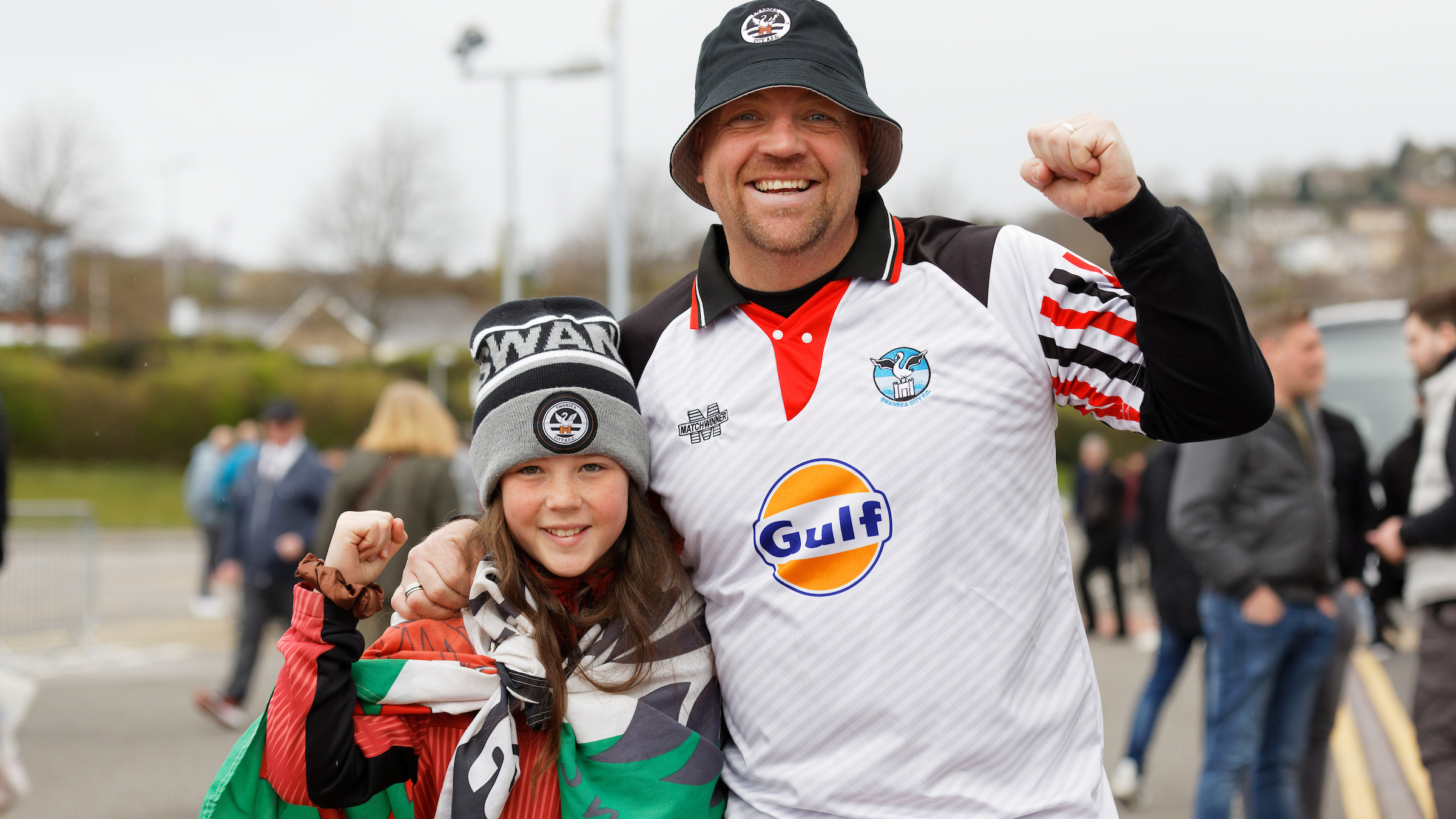 A young girl and her dad in Swans gear smile at the camera 