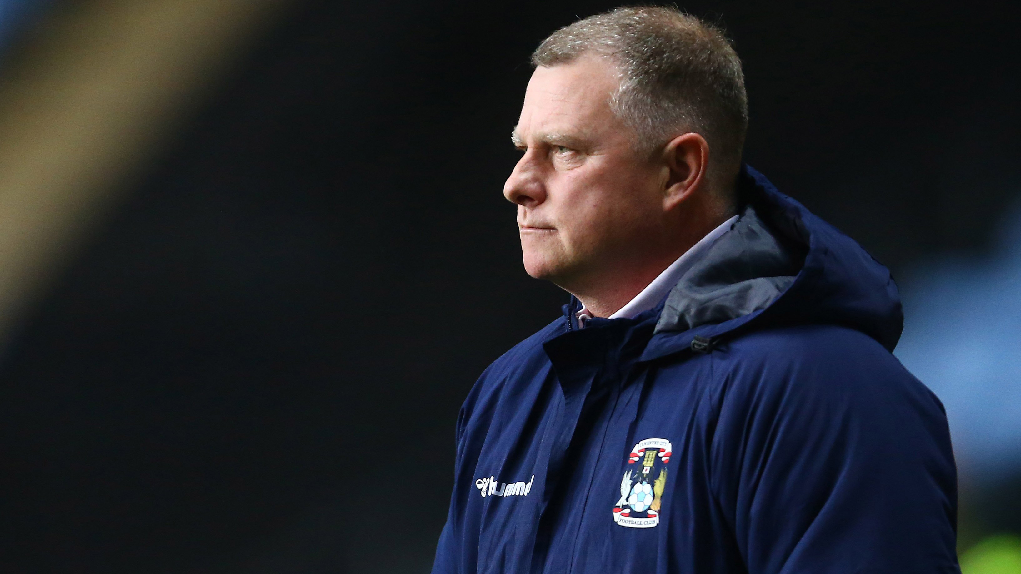 Coventry manager Mark Robins wears club coat while watching his team
