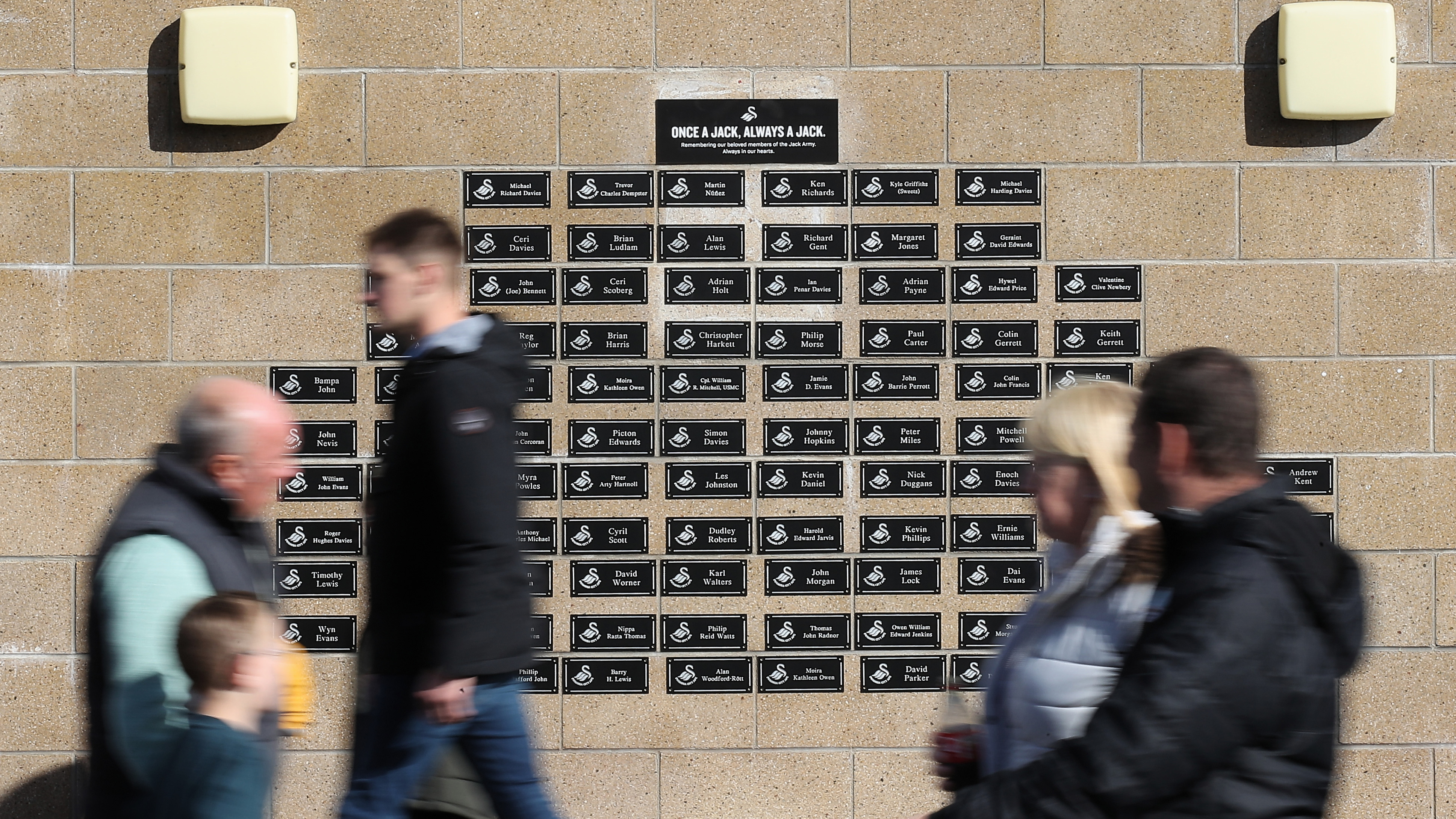 Fans walk past the memory wall at the Swansea.com Stadium 