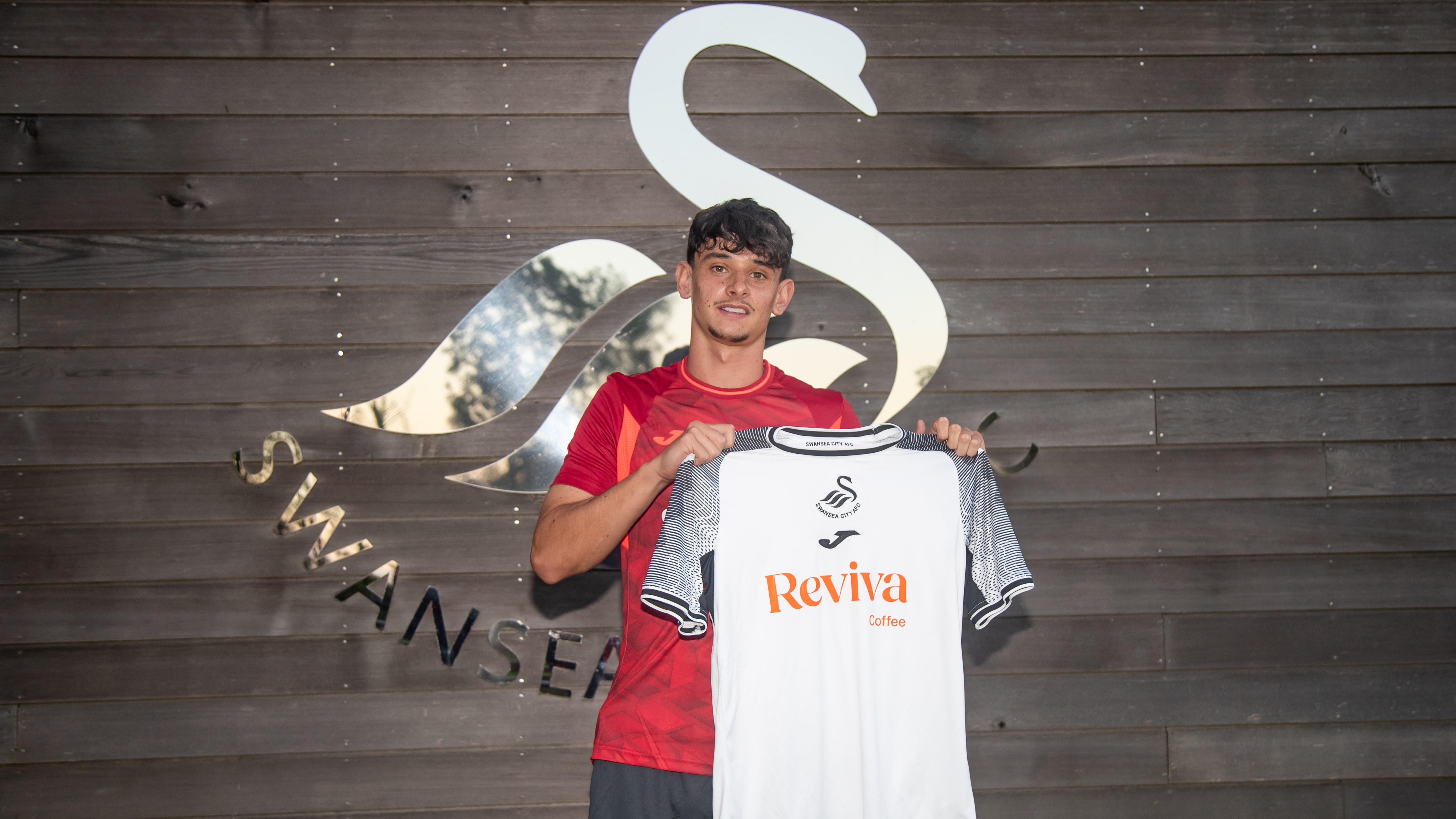 Charlie Patino holds up Swansea City home shirt