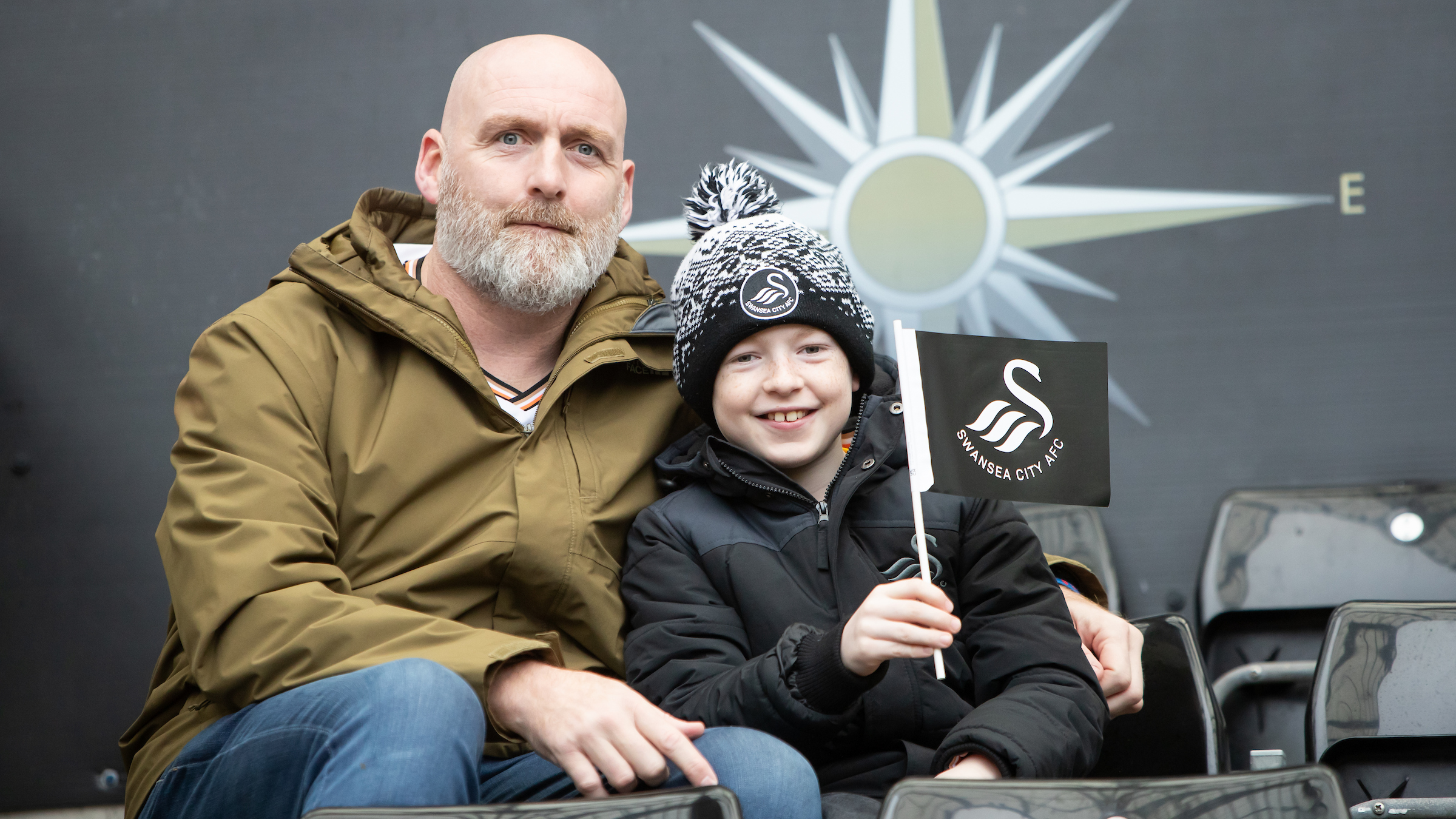 An adult and child supporting the Swans at the Swansea.com Stadium