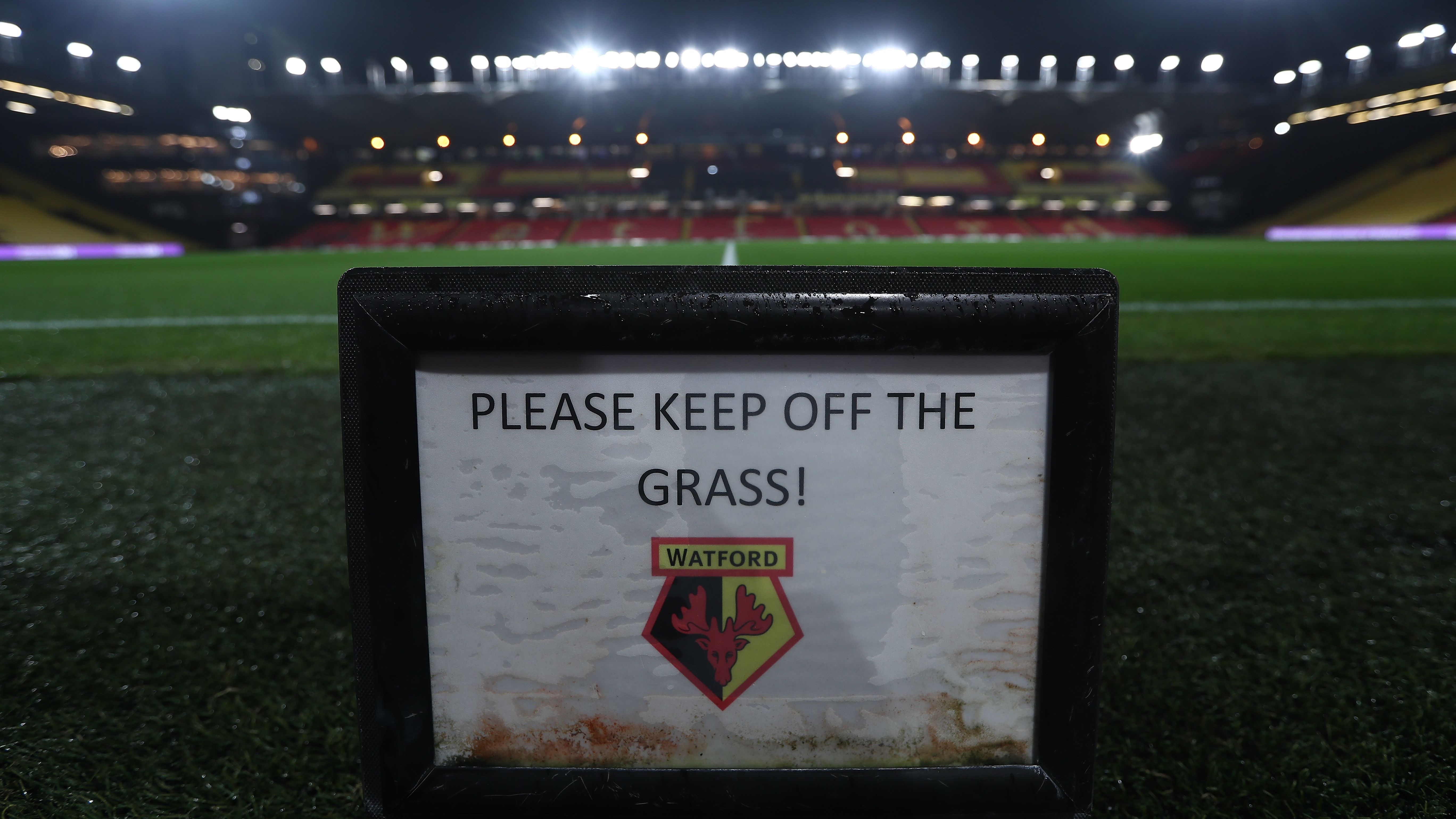 Watford stadium in the evening with keep off the grass sign