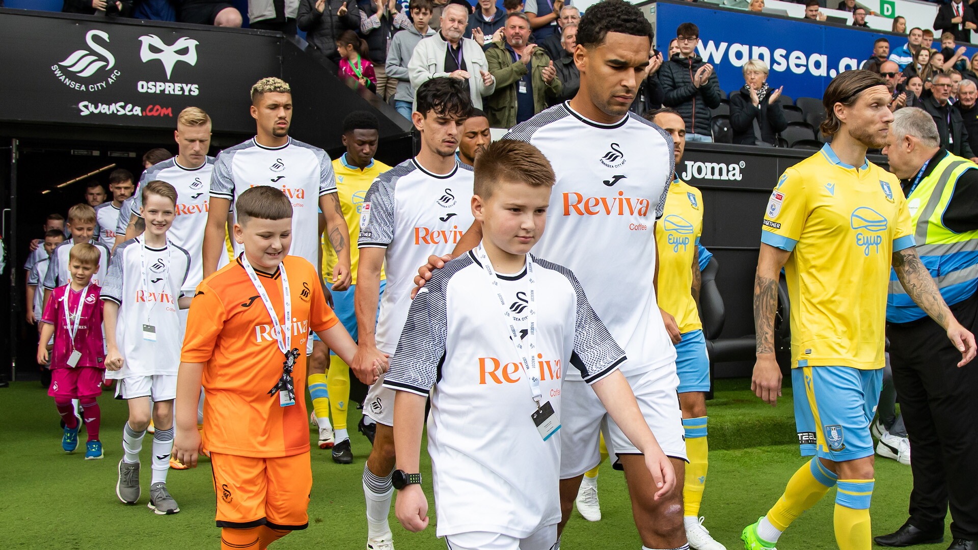 home mascots walking out with Ben Cabango in Swansea.com stadium