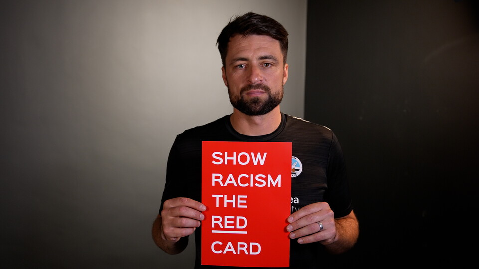 Russell Martin holds a show racism the red card card
