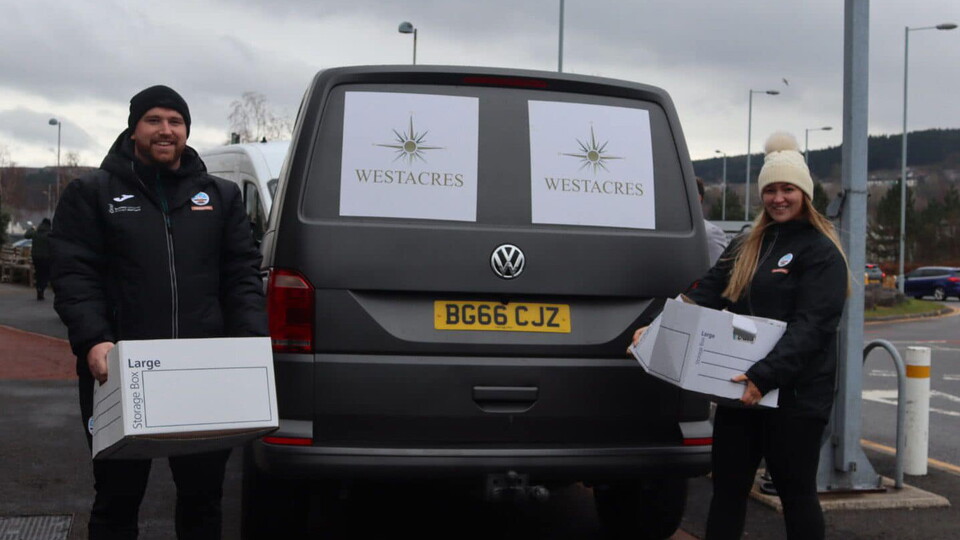 Foundation staff holding boxes of food next to Westacres van