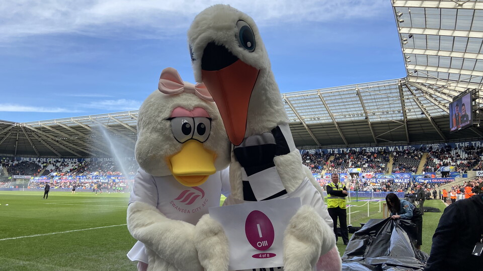 Cyril and Cybil holding an Easter Egg with the letter "I" on it.