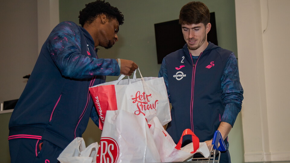 Josh Key and Nat Ogbeta pack bags at Sketty Foodbank