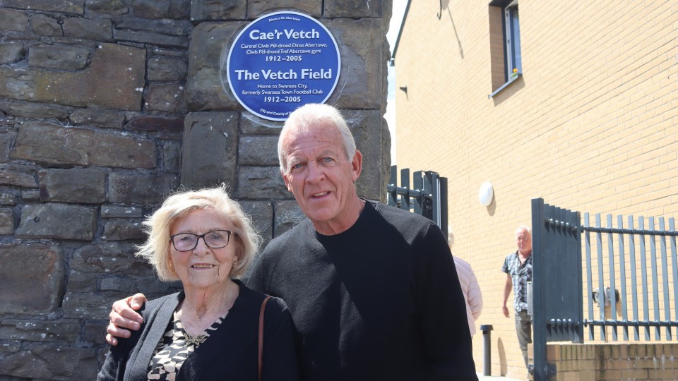 Esme Allchurch and Alan Curtis in front of the Vetch Field blue plaque 