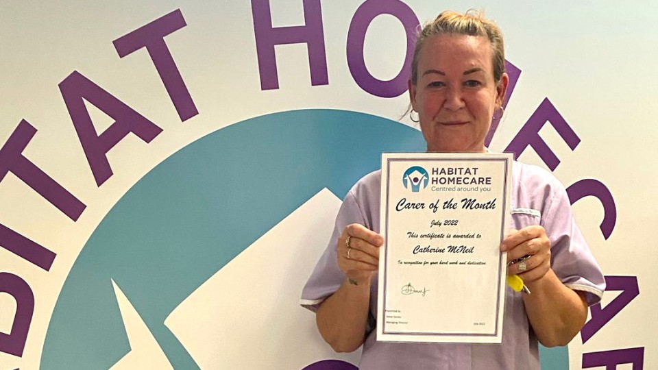 Cath holds up her carer of the month certificate