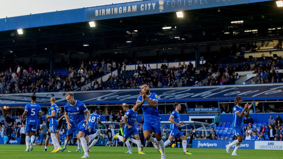 Birmingham City players warm up with fans in the background