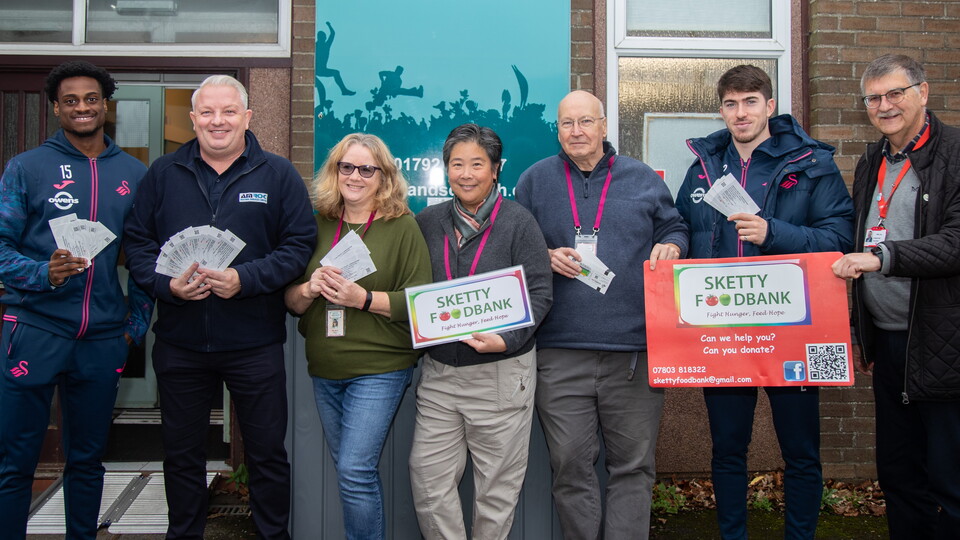 Nat Ogbeta, Josh Key, Jason from AMROC Heating and Kim and Audrey from Sketty Foodbank stand outside the foodbank holding tickets