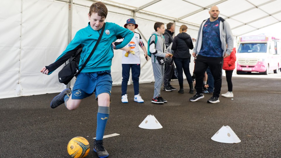 Young fan kicks a football at fan park
