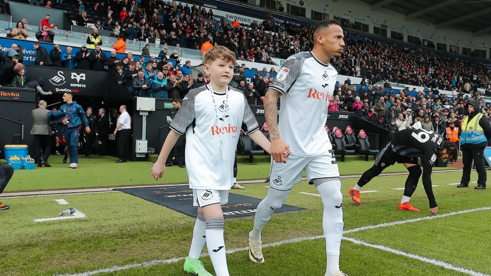 Ronald leading out a mascot during the 2023-24 season