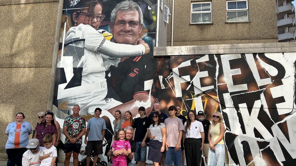 A group of people who made the mural happen in front of the mural 