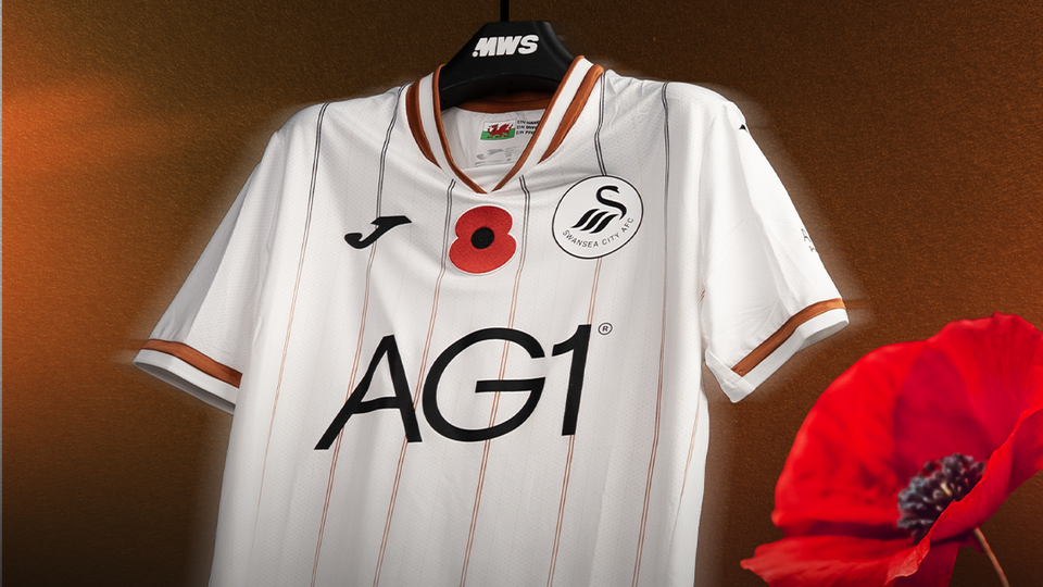 White football shirt with red poppy displayed on a brown background.
